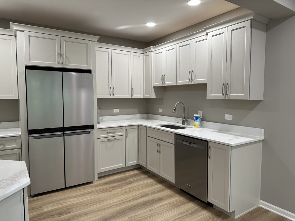 This is an image of a kitchen with sink, refrigerator, built-in cabinets. This is a galley-style kitchens or lavish wet bars