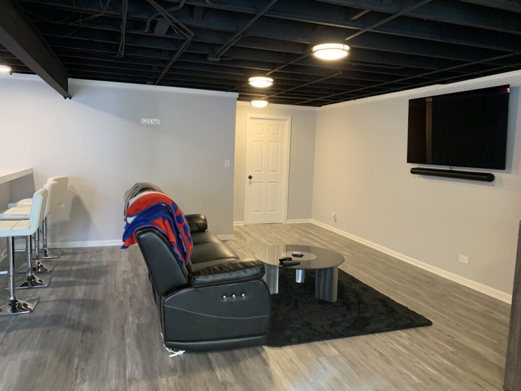 Image of a basement renovation featuring living area with sofa and television.