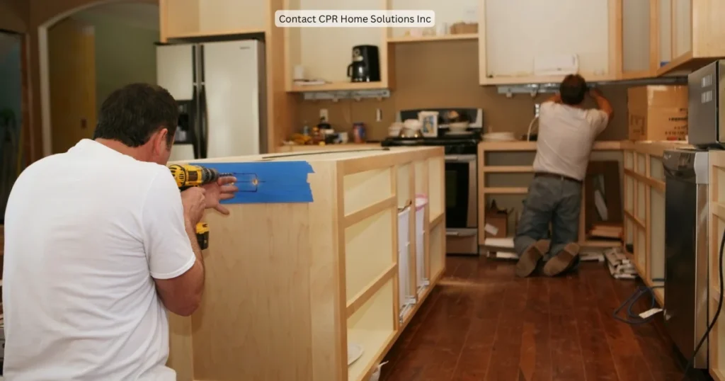 Two contractors install cabinetry and assemble a kitchen island in the early stages of a kitchen remodel illustrating cabinet installation, kitchen renovation planning and custom kitchen construction. 
