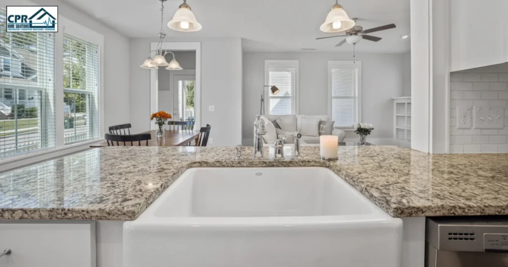 Large granite countertop with a bright contemporary kitchen and apron-front sink. Elegant colors of countertops, durable kitchen surfaces, quartz and granite options, open concept kitchen design.